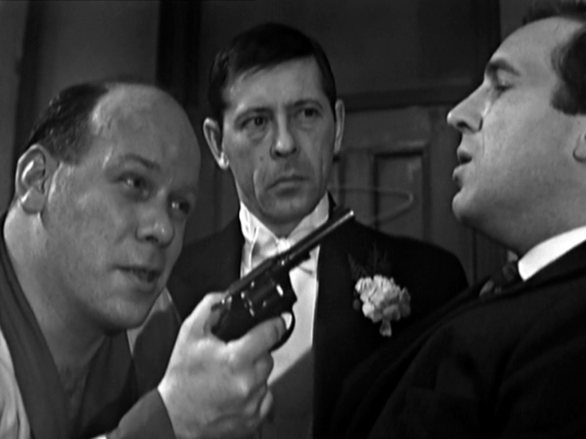 Heavy Zibbo waves a gun in Dr Keel's face